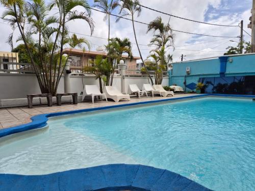 a large swimming pool with chairs and palm trees at Mountview Tourist Residence in Quatre Bornes