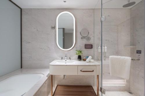 a bathroom with a sink and a tub and a mirror at Sunworld Dynasty Hotel Beijing Wangfujing in Beijing