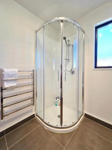 a glass shower in a bathroom with a window at Kingfisher Lodge in Lake Tekapo