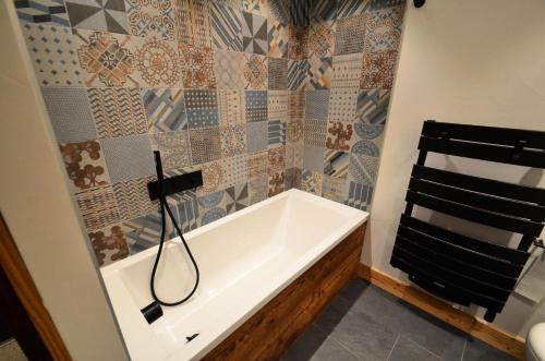 bagno con vasca e parete piastrellata di Chalet L'etable - CHALET | SAINT-MARTIN-DE-BELLEVILLE MAE-4304 a Saint-Martin-de-Belleville