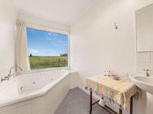 a bathroom with a tub and a sink and a window at Abington Farm in Heyfield