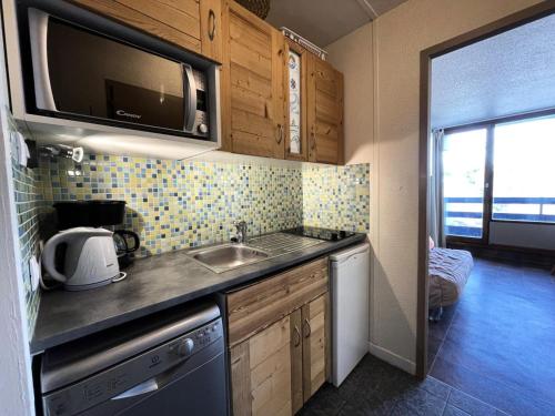 une petite cuisine avec un évier et un micro-ondes dans l'établissement Résidence Chaviere - Studio avec petit balcon et baignoire au pied des pistes MAE-4264, aux Menuires