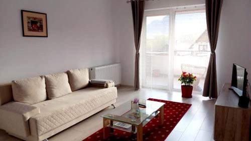 a living room with a white couch and a glass table at Piatra Craiului Residence Zărnești in Zărneşti