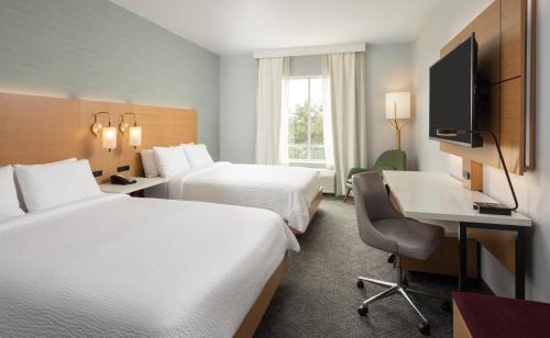 a hotel room with two beds and a desk at DoubleTree by Hilton Houston Westchase in Houston