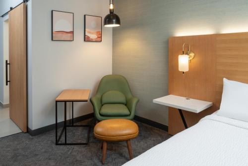 a hotel room with a bed and a green chair at DoubleTree by Hilton Houston Westchase in Houston