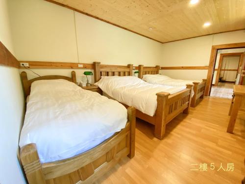 two twin beds in a room with wooden floors at Taoyuan Villa B&B in Puli
