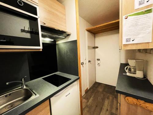 eine kleine Küche mit einer Spüle und einer Mikrowelle in der Unterkunft Résidence Lac Du Lou - Studio pour 4 Personnes 214 in Les Menuires
