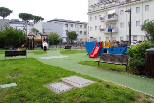 een park met een speeltuin met een glijbaan en banken bij Piazza Marconi Attico Duplex per 5 persone in Lido di Jesolo
