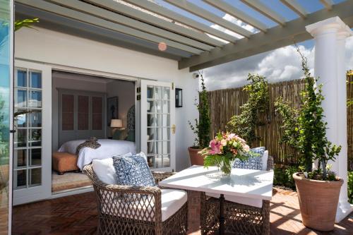 a patio with a table and chairs and a bed at La Fontaine Guest House Hermanus in Hermanus