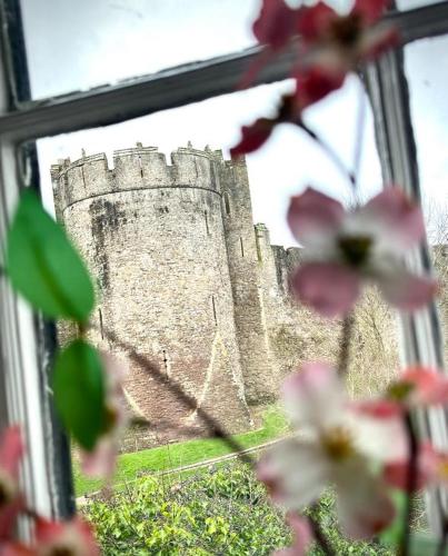 a castle is seen through a window with pink flowers at The Three Tuns in Chepstow