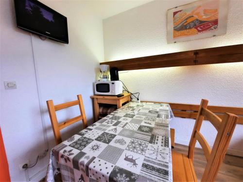 une salle à manger avec une table et un four micro-ondes dans l'établissement Résidence Chaviere - Studio 2 pers - ski au pied - à la Croisette MAE-6004, aux Menuires