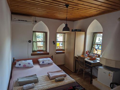 a bedroom with a bed and a desk and windows at National Monument Konak in Stolac