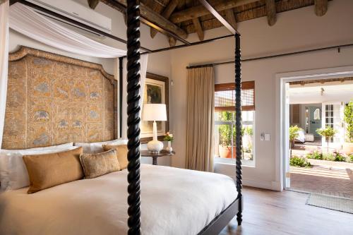 a bedroom with a four poster bed and a window at La Fontaine Guest House Hermanus in Hermanus