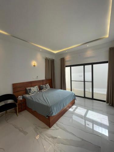- une chambre avec un lit et une grande fenêtre dans l'établissement Résidence ADJIBADE, à Cotonou