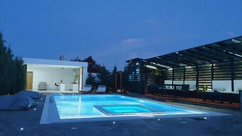 a large swimming pool in a backyard at night at One Bedroom Pool House by Olivujoj in Anavissos