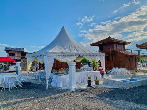 a white tent with tables and chairs in front of a building at HOMESTAY KAYU in Kajang