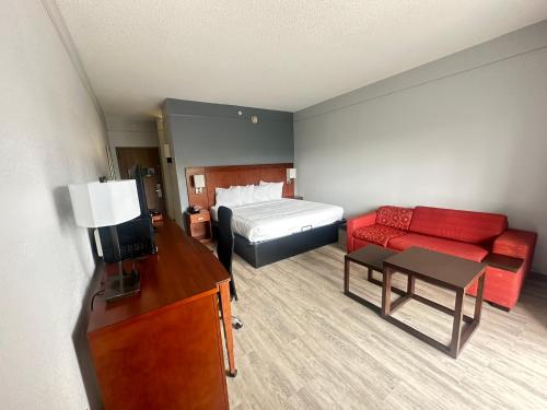 a hotel room with a bed and a red couch at Super 8 by Wyndham Dallas Love Field Airport in Dallas