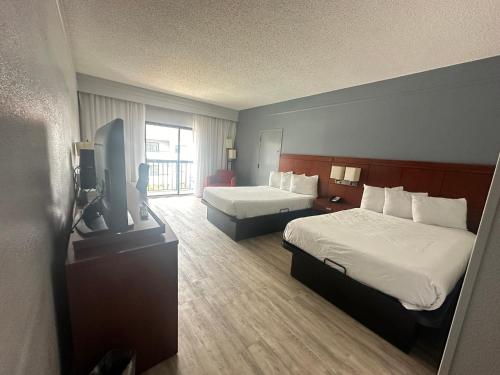 a hotel room with two beds and a flat screen tv at Super 8 by Wyndham Dallas Love Field Airport in Dallas