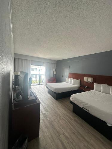 a hotel room with two beds and a television at Super 8 by Wyndham Dallas Love Field Airport in Dallas