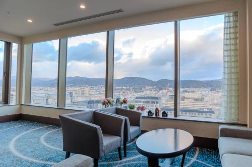 Zimmer mit einem großen Fenster mit Stühlen und einem Tisch in der Unterkunft Hotel Keihan Kyoto Grande in Kyoto