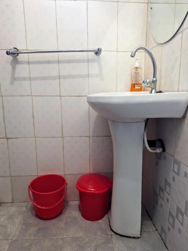 a bathroom with a sink and two red buckets at Kiamboni in Nakuru