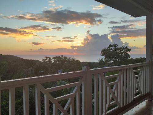 a view of the ocean from a porch at sunset at Villa vue de rêve mer & forêt primaire in Les Trois-Îlets