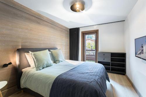 een slaapkamer met een bed met een houten muur bij Résidence Stallion A - 3 Pièces pour 4 Personnes 464 in Megève