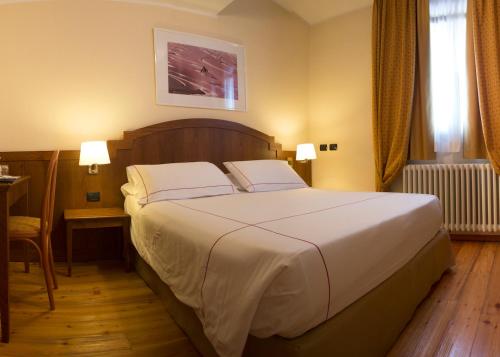 a bedroom with a large white bed with two pillows at Cresta Et Duc Hotel in Courmayeur