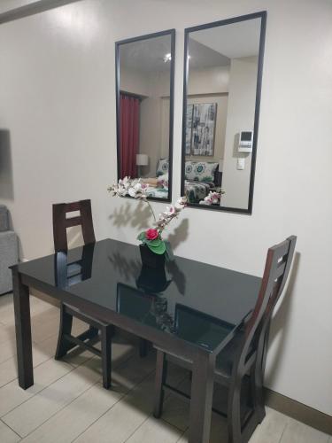een glazen tafel met 2 stoelen en een spiegel bij Condotel Near Airport Pasay City in Manilla