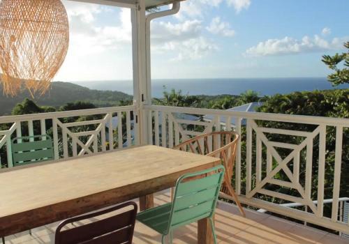 a porch with a wooden table and chairs and the ocean at Villa vue de rêve mer & forêt primaire in Les Trois-Îlets