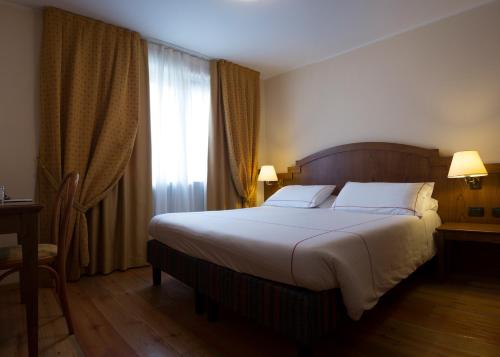 a bedroom with a large bed and a window at Cresta Et Duc Hotel in Courmayeur
