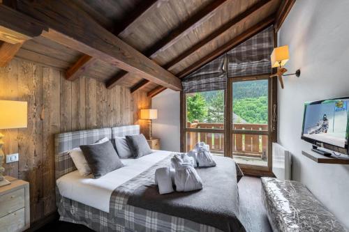 a bedroom with a large bed and a television at Résidence Saint Joseph - Chalets pour 10 Personnes 164 in Les Allues