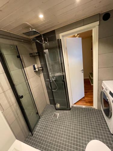 a bathroom with a shower and a washing machine at Idyllinen puutaloasunto in Vaasa