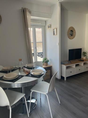 une salle à manger avec une table, des chaises et une télévision dans l'établissement Le cosy de la Dent du Chat - Classé 3 étoiles - Hyper centre Aix les Bains, à Aix-les-Bains