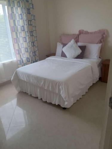 a bedroom with a bed with white sheets and pillows at 3/45 Oxley Road in Port Edward