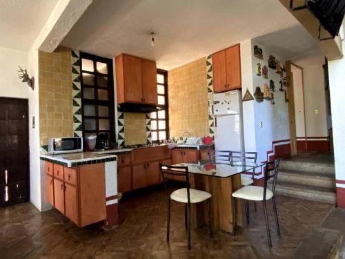 eine Küche mit Holzschränken sowie einem Tisch und Stühlen in der Unterkunft Cabaña de las esferas en Mazamitla in Mazamitla