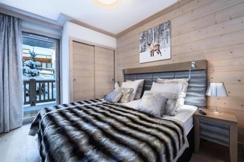 1 dormitorio con 1 cama grande y pared de madera en Résidence Carre Blanc - 3 Pièces pour 6 Personnes 474, en Courchevel