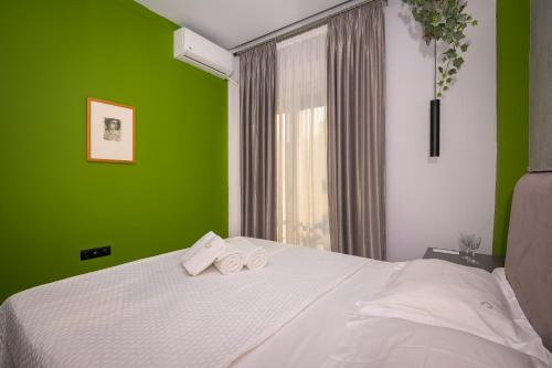 Un dormitorio verde con una cama con toallas. en Pelagio apart 2 by homebrain en Alejandrópolis