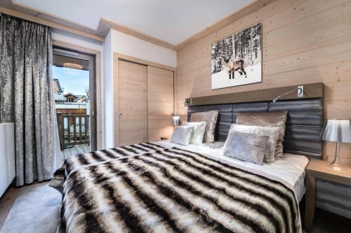 a bedroom with a large bed with a striped blanket at Résidence Carre Blanc - 3 Pièces pour 6 Personnes 394 in Courchevel