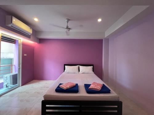 a bedroom with purple walls and a bed with two pillows at Bonita House in Bangkok