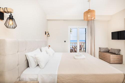 a bedroom with a white bed with a view of the ocean at Manthos Beachfront Apartments in Laganas