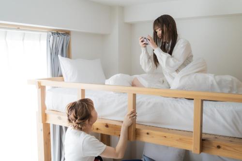 a woman taking a picture of a woman sitting on a bed at DD HOTEL 中洲 in Fukuoka