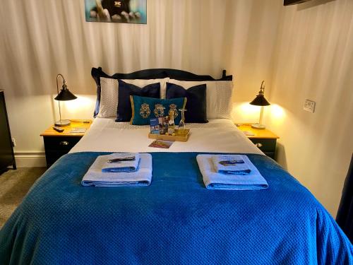 a bedroom with a blue bed with two towels on it at The Sapling in Delabole