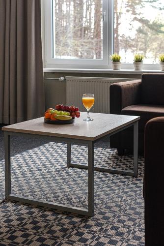 a table with a glass of wine and a plate of food at Nykščio Namai & SPA in Anykščiai