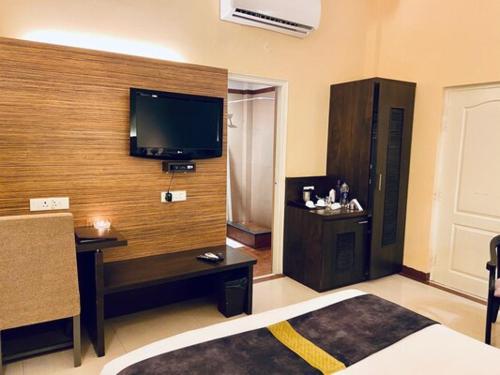 a hotel room with a television on a wall at Status Club Resort in Kānpur