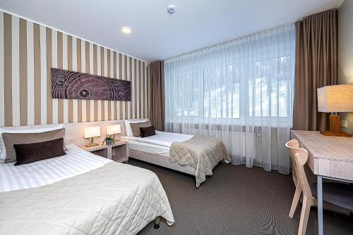 a hotel room with two beds and a desk at Nykščio Namai & SPA in Anykščiai