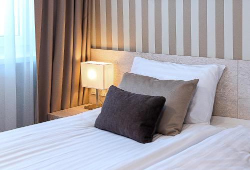 a bedroom with a bed with two pillows and a lamp at Nykščio Namai & SPA in Anykščiai