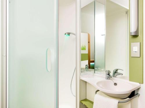 La salle de bains est pourvue d'un lavabo et d'un miroir. dans l'établissement Ibis Budget Roanne Hôtel, à Roanne