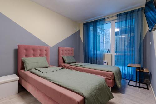 two beds in a room with blue curtains at Mirela Guest Apartment in Veliko Tŭrnovo