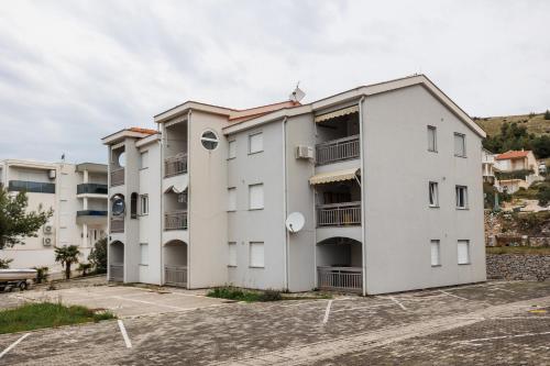 a white apartment building with a parking lot at Sunset Apartman Ana in Zaboric